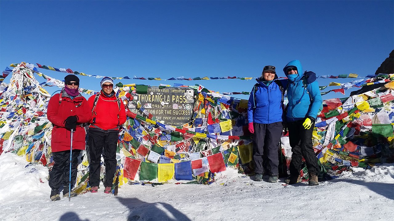 Trekkers on the top of Thorong-La pass at an altitude of 5416 m are getting ready for a picture to be taken with the board in the middle.